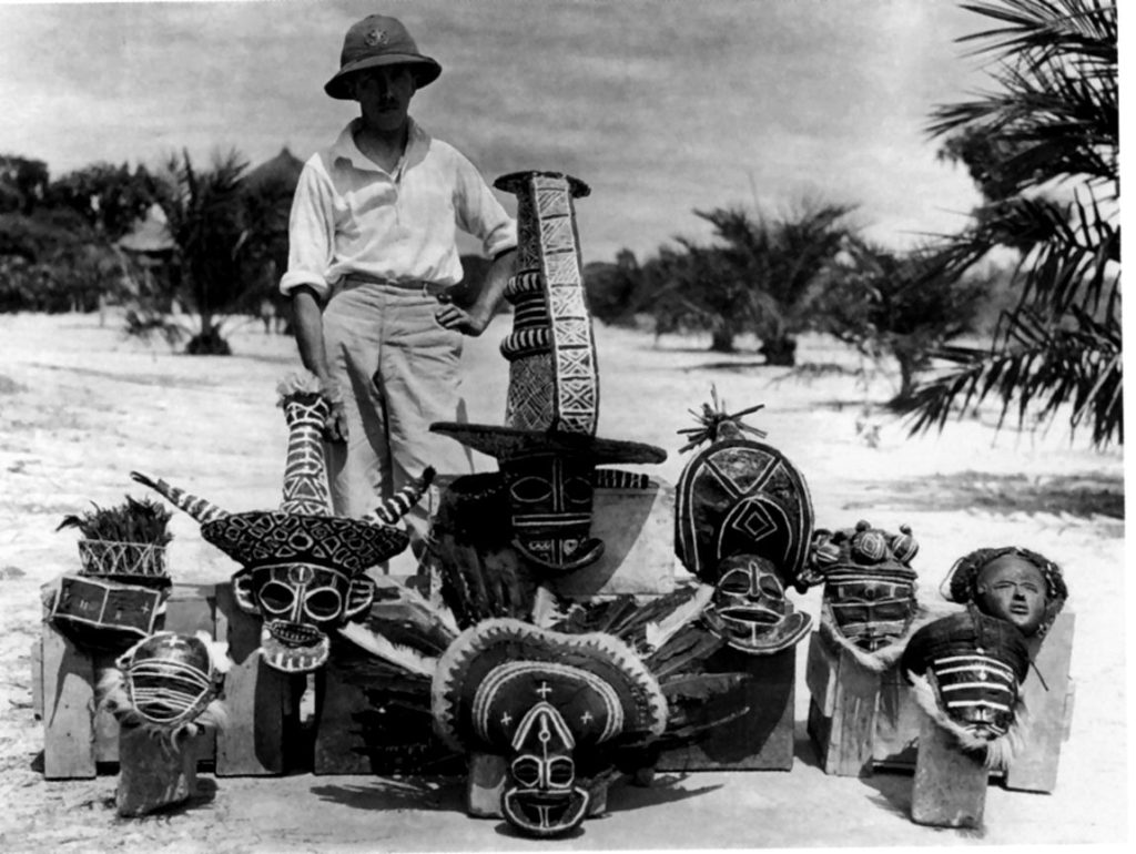 G. De Witte pose au milieu des trophées (masques CHOKWE de la société d’initiation mukanda) (RDC)