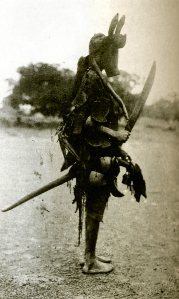 Danseur masqué tenant entre ses jambes un bâton à tête d’équidé (Bamana – Mali)